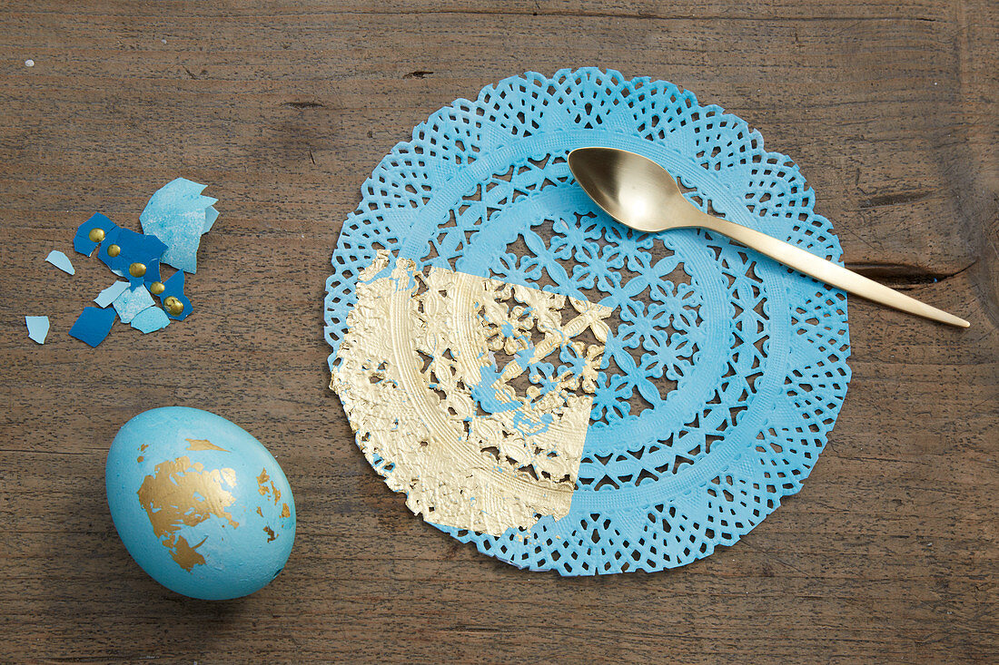 Osterei und Tortenspitze dekoriert in Blau und Gold
