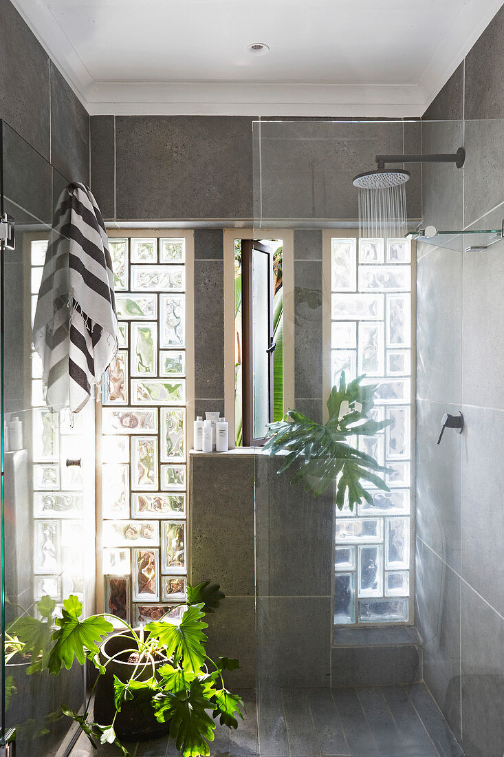 Shower area in bathroom with glass brick windows and concrete-effect walls