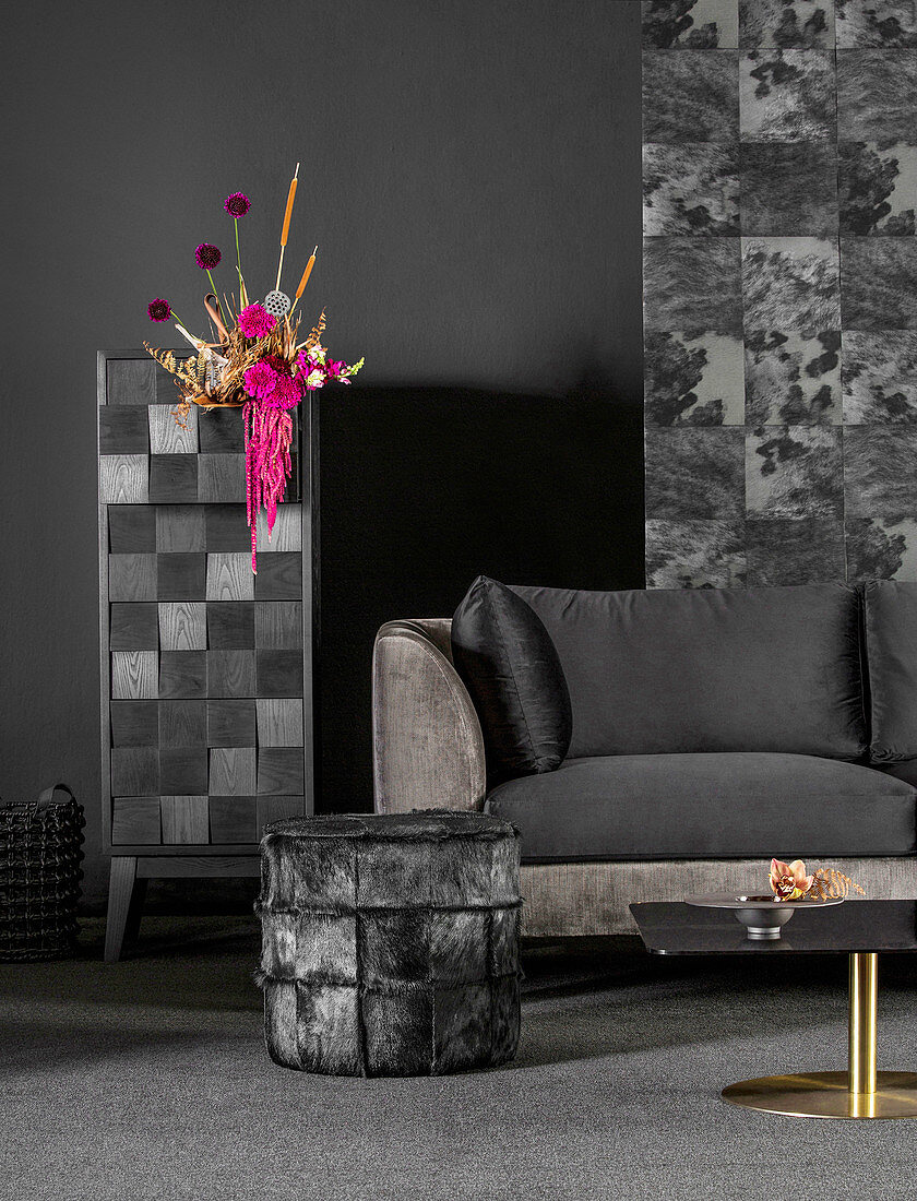 Back velvet sofa, stool and flower arrangement on cabinet
