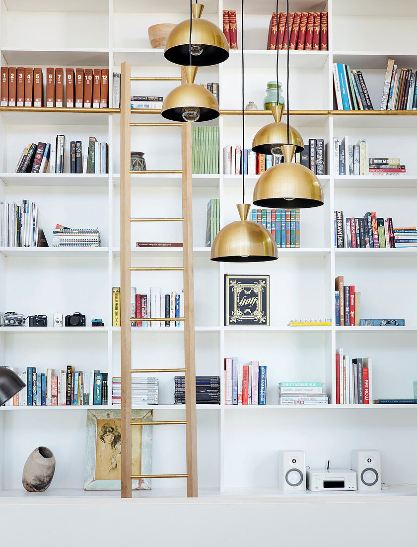 Library ladder and pendant lamps in front of white shelves