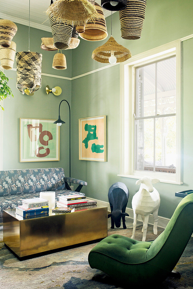 Grün gepolsterter Sesssel, Tierfiguren, Couchtisch und Sofa in Lounge mit grün getönter Wänden