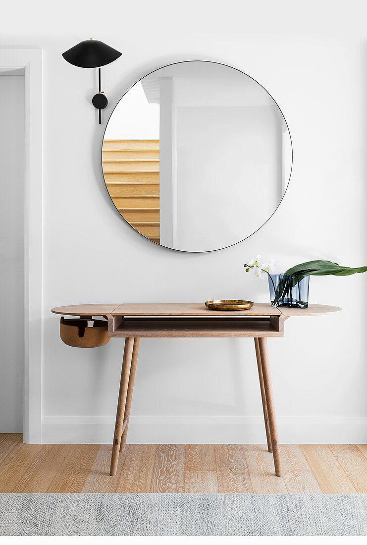 Designer-Wandtisch unter rundem Spiegel und schwarzem Wandleuchte