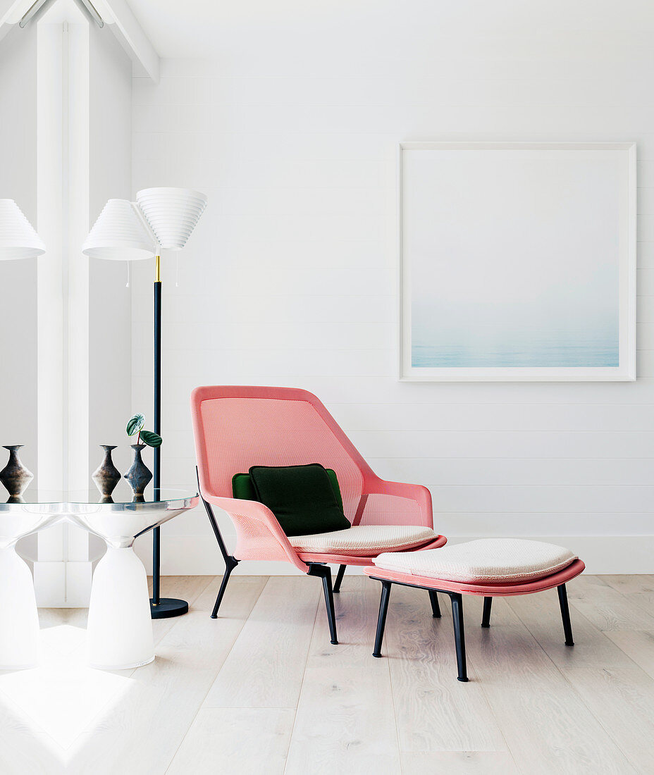 Designer-Sessel mit Fusshocker neben Stehlampe und Beistelltisch in Zimmerecke