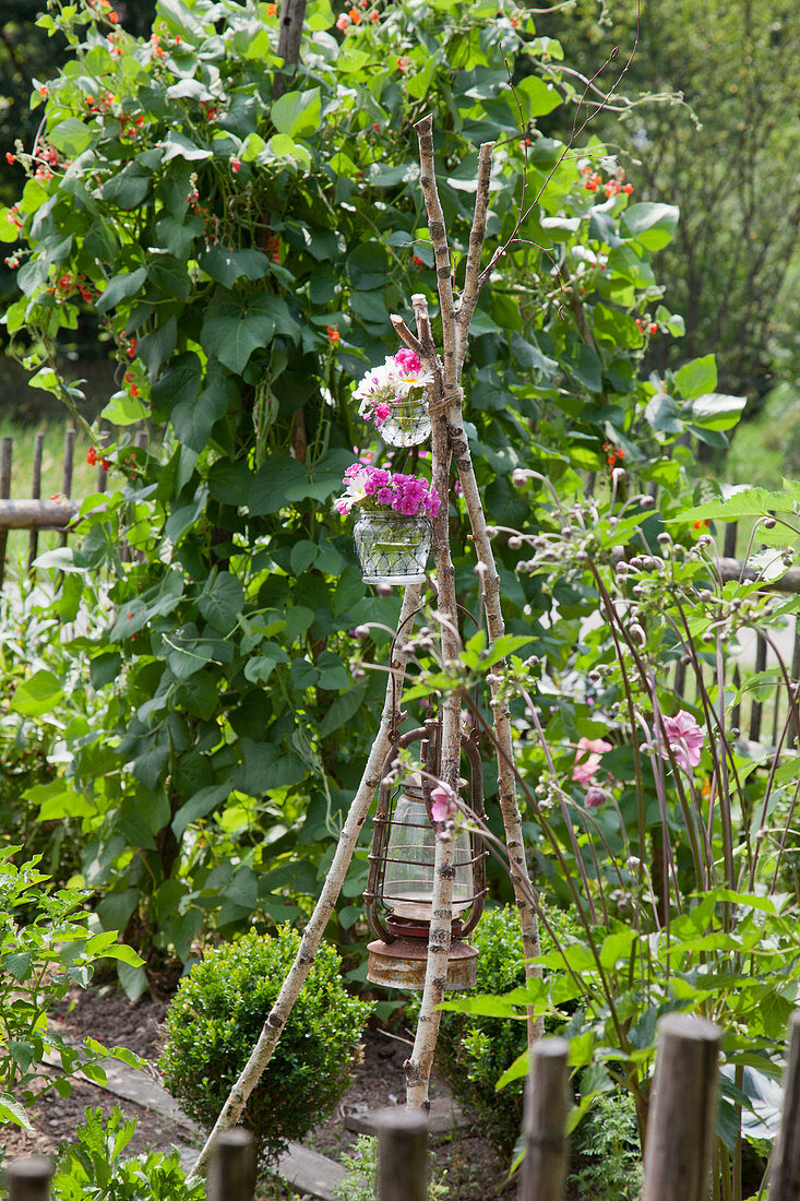 DIY-Blumenstellage mit blühenden Margeriten und Phlox im Garten