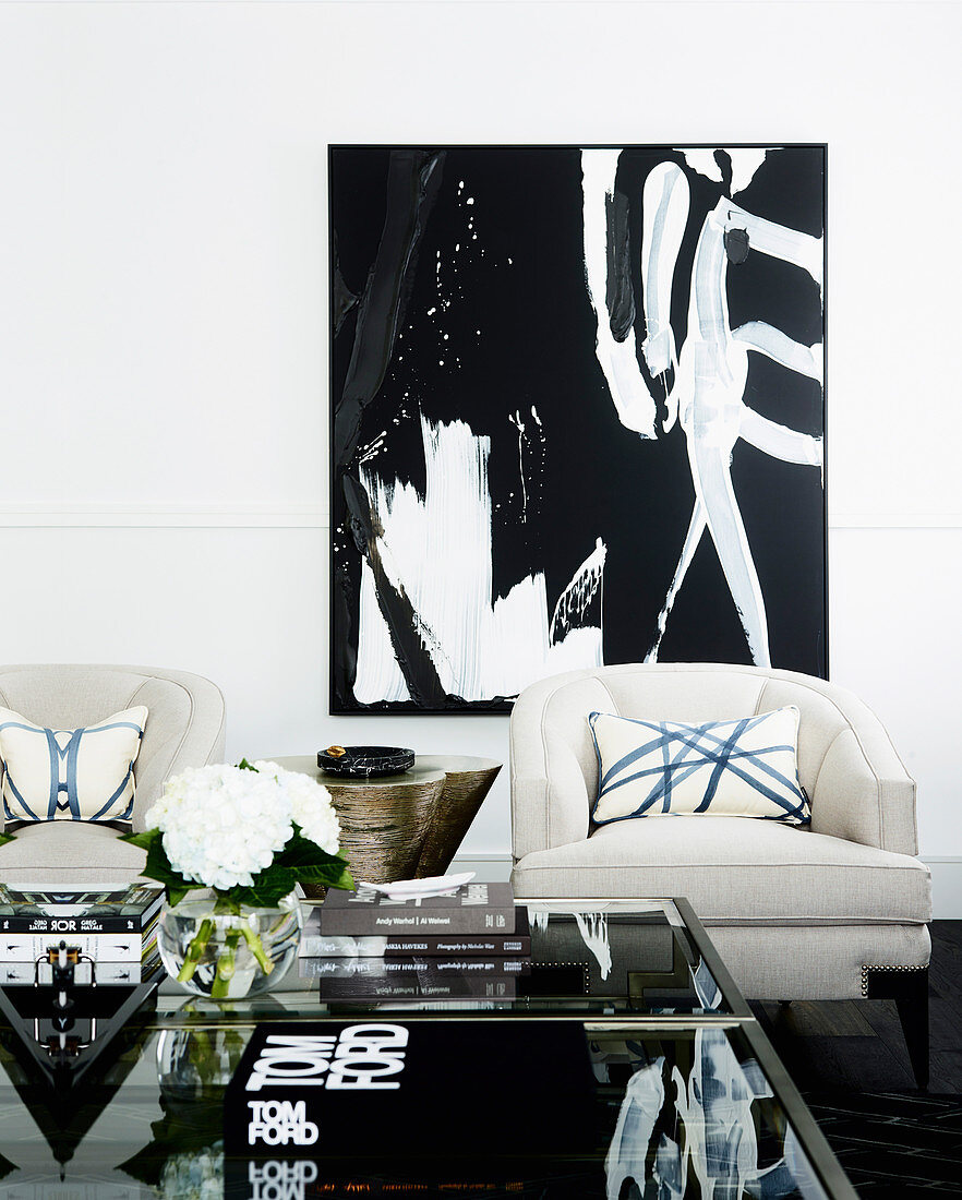Couch, armchair with cushions, side table and artwork on the white wall in the living room