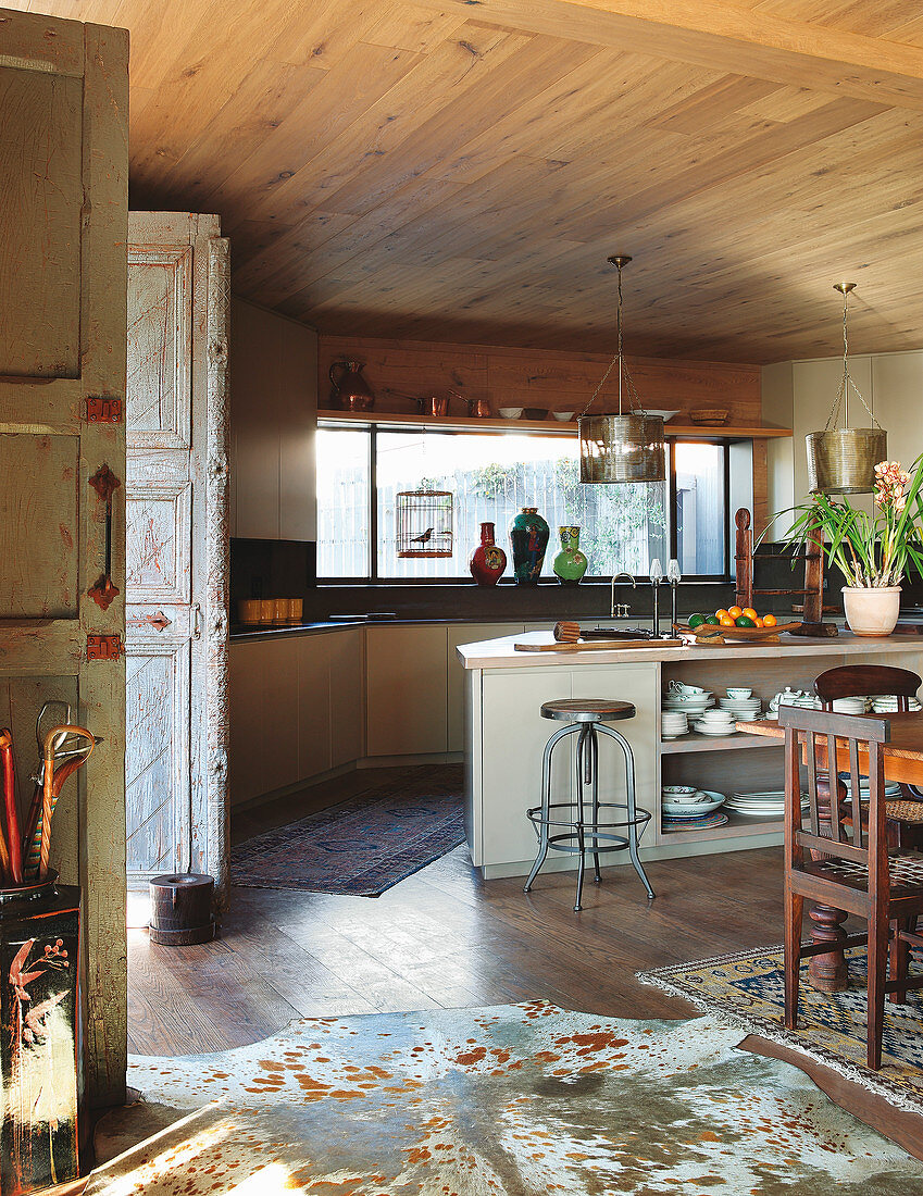 Counter, wooden ceiling and cowhide rug in open-plan kitchen