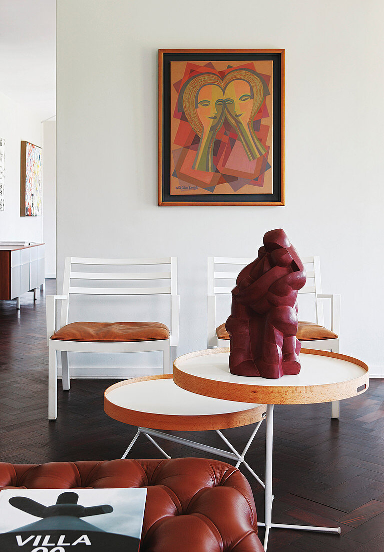 Sculpture on side table, two chairs and artwork on wall