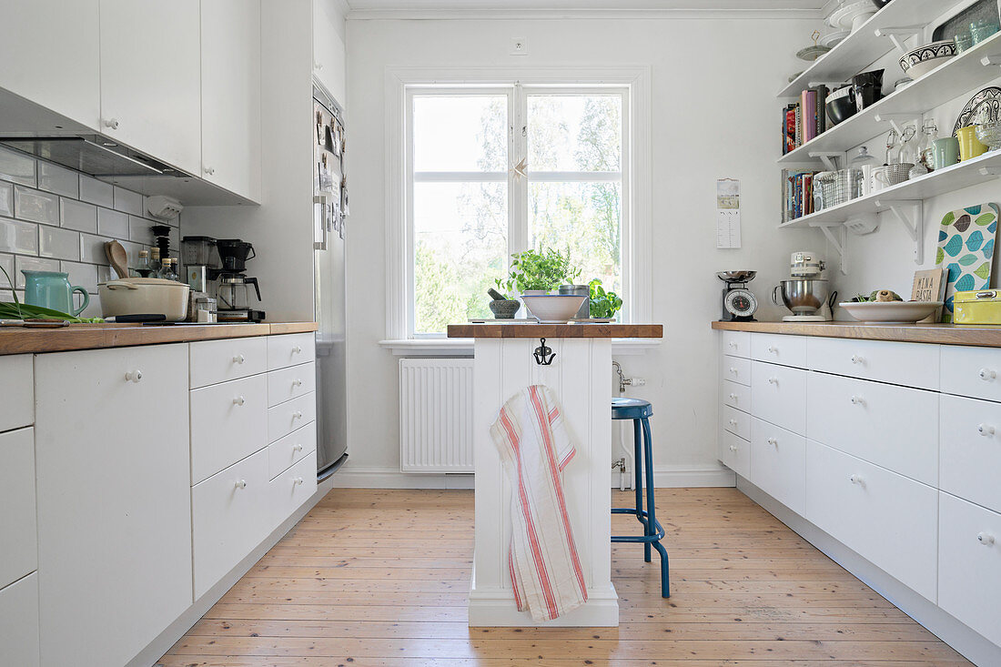 Schmale Kücheninsel in weißer Küche mit Regalen