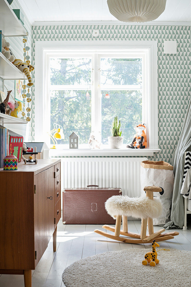 Graphic wallpaper and vintage-style furniture in bright child's bedroom