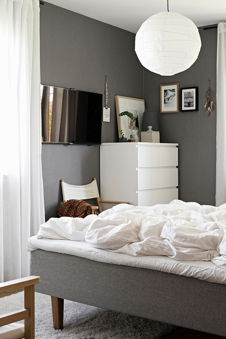 Blick ins Schlafzimmer mit weißer Kommode und grauen Wänden