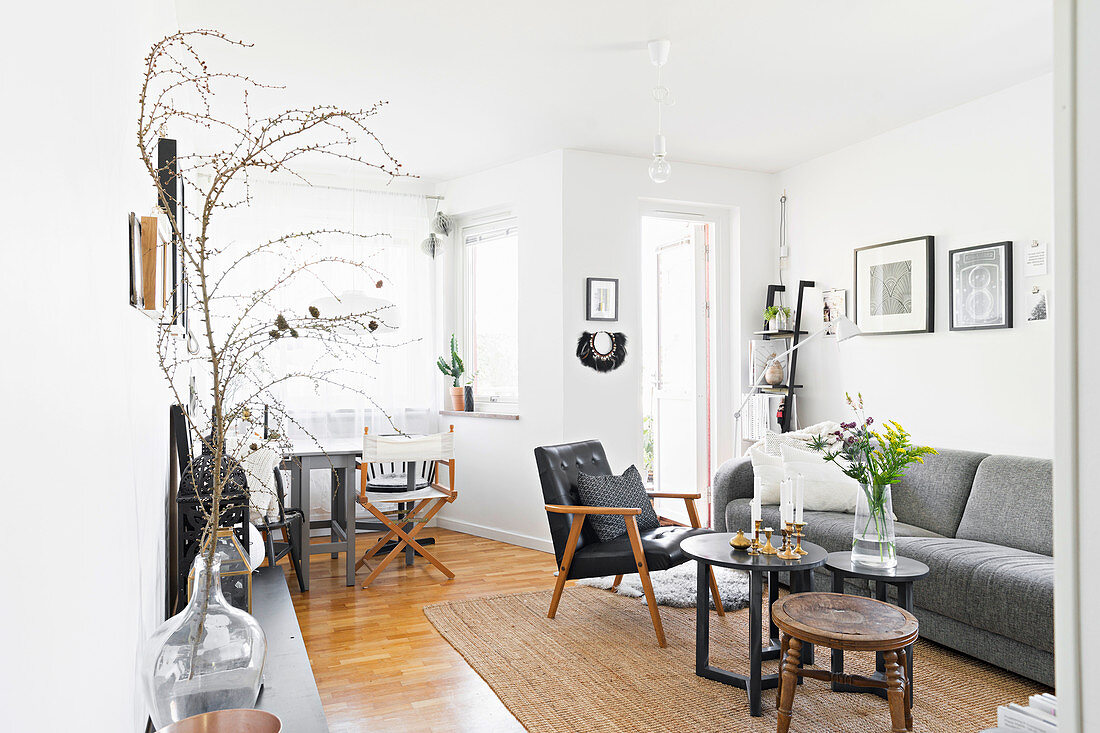 Graues Polstersofa, Lederstuhl und Coffeetable im Wohnzimmer mit weißer Wand