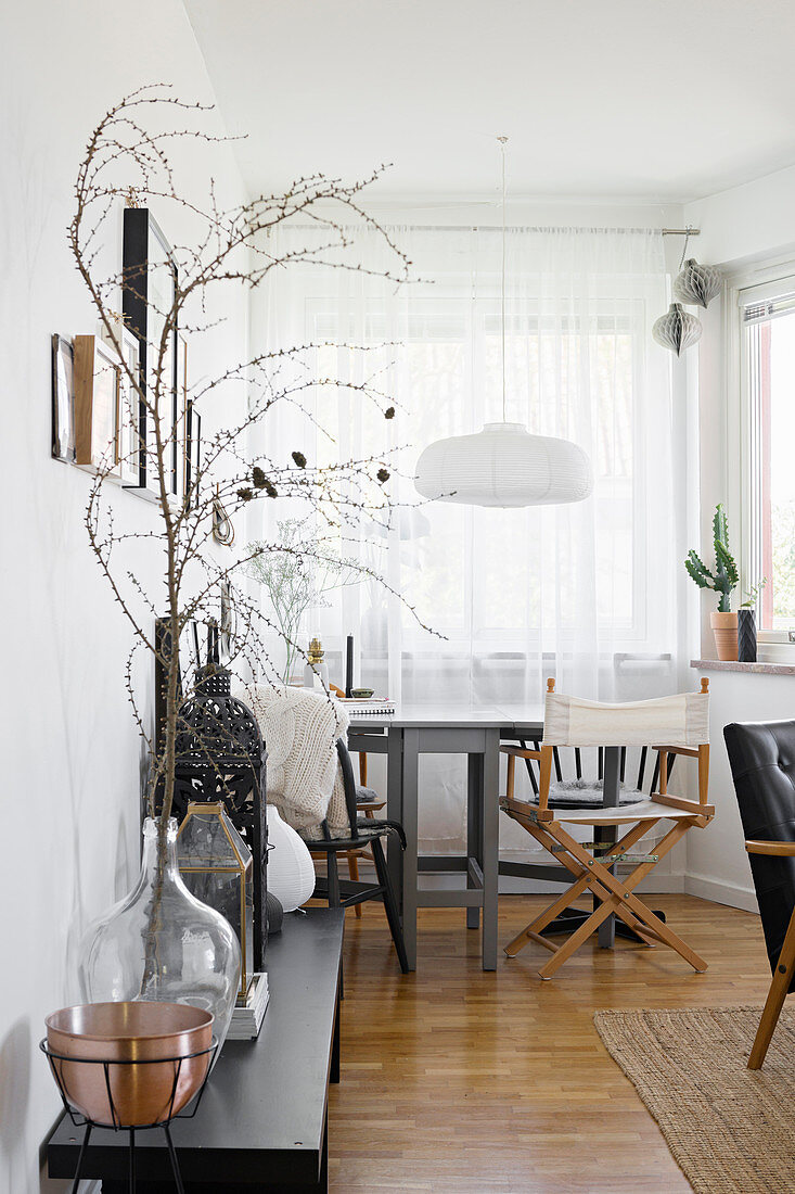 Demijohn and lantern on wooden bench with dining area next to window in background