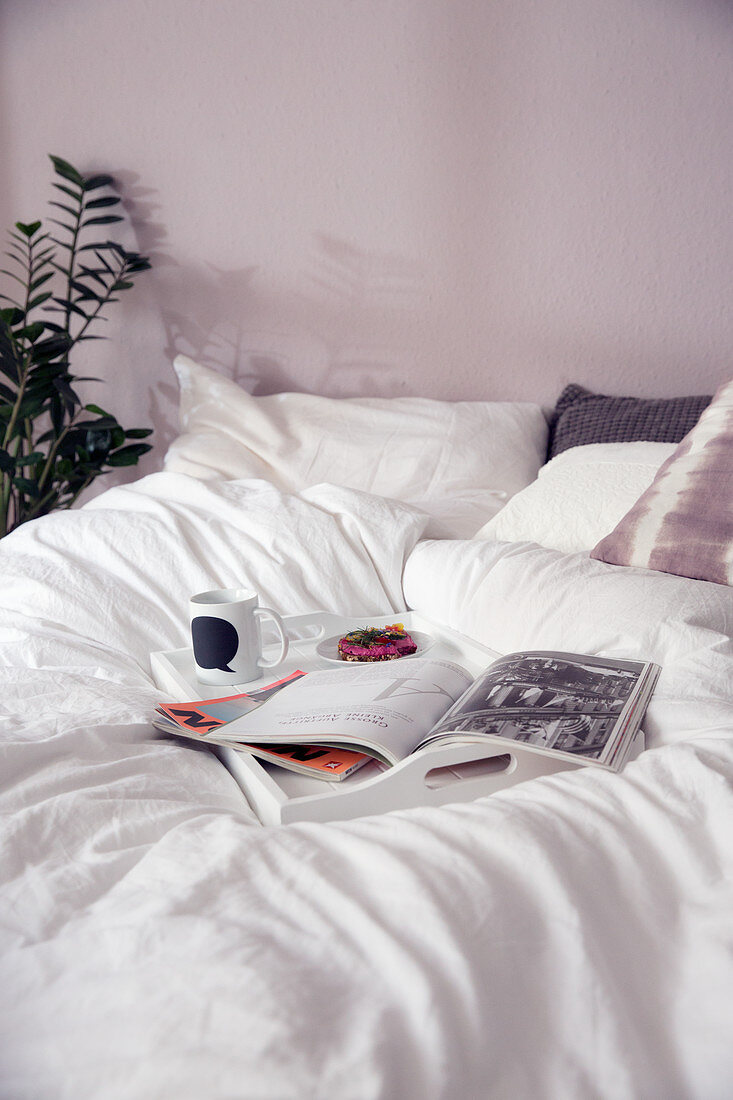 Frühstückstablett mit Zeitschrift auf Bett