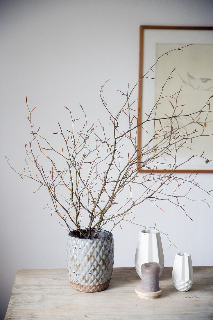 Vase mit Zweigen auf Holztisch