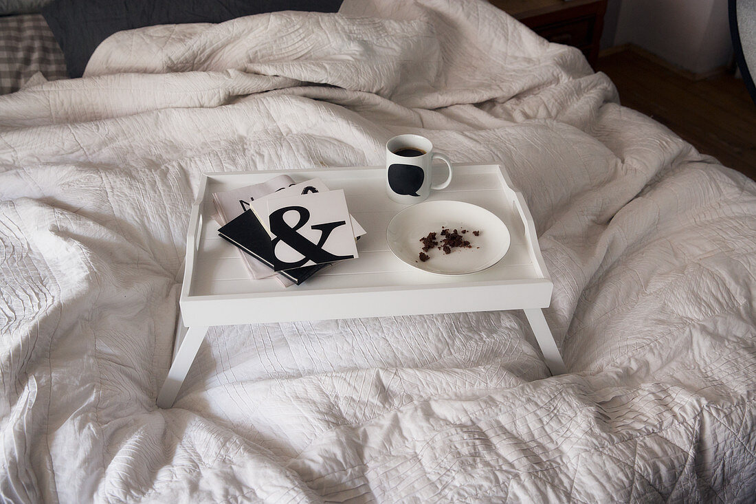 Frühstückstablett mit schwarz-weißen Utensilien auf dem Bett