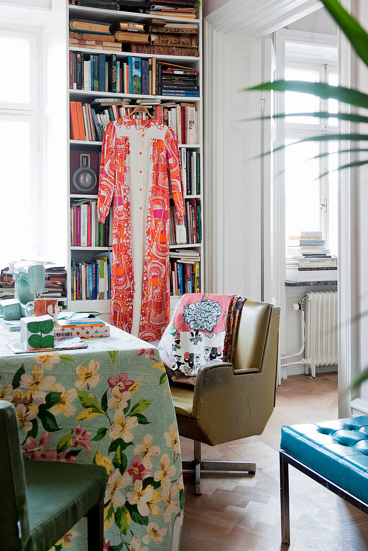 Retro armchair at table with floral tablecloth in front of bookcase