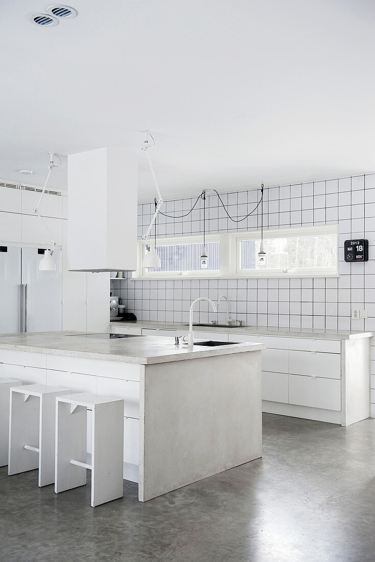 Island counter and concrete worksurfaces in white kitchen