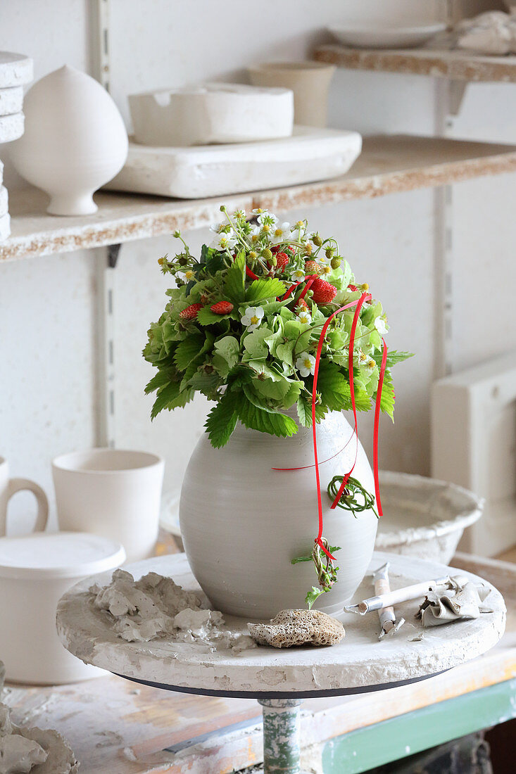 Bouquet of strawberry plants in clay vase