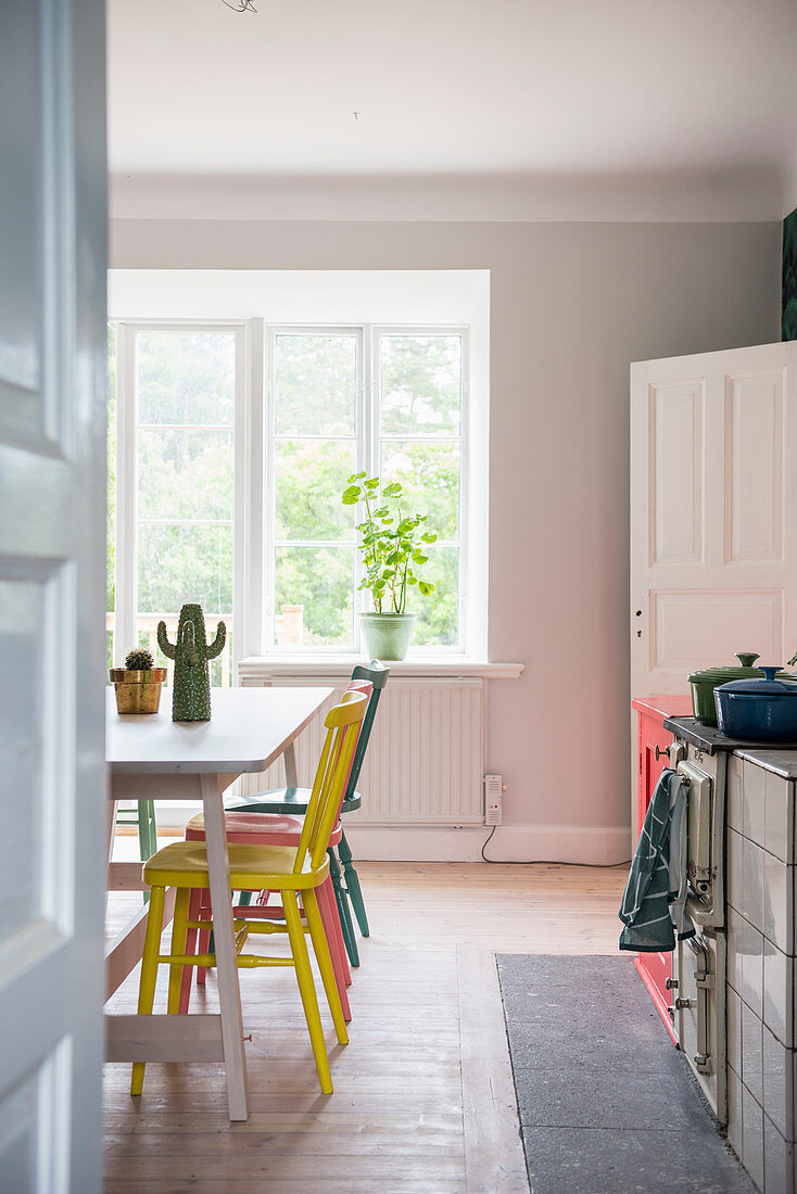 Blick in die Küche mit bunten Stühlen am Tisch vor dem Fenster