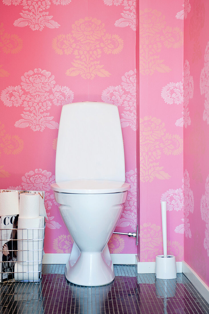 Toilette vor pinker Tapete mit Blumenmuster