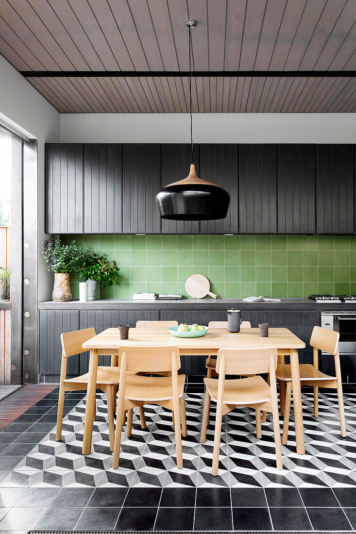 Dining area in front of a black kitchenette with green wall tiles