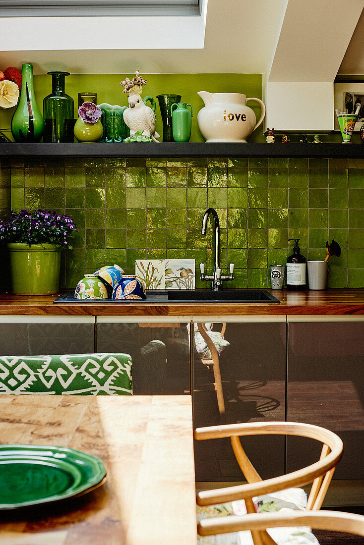 View across dining table to kitchen counter with green tiled splashback