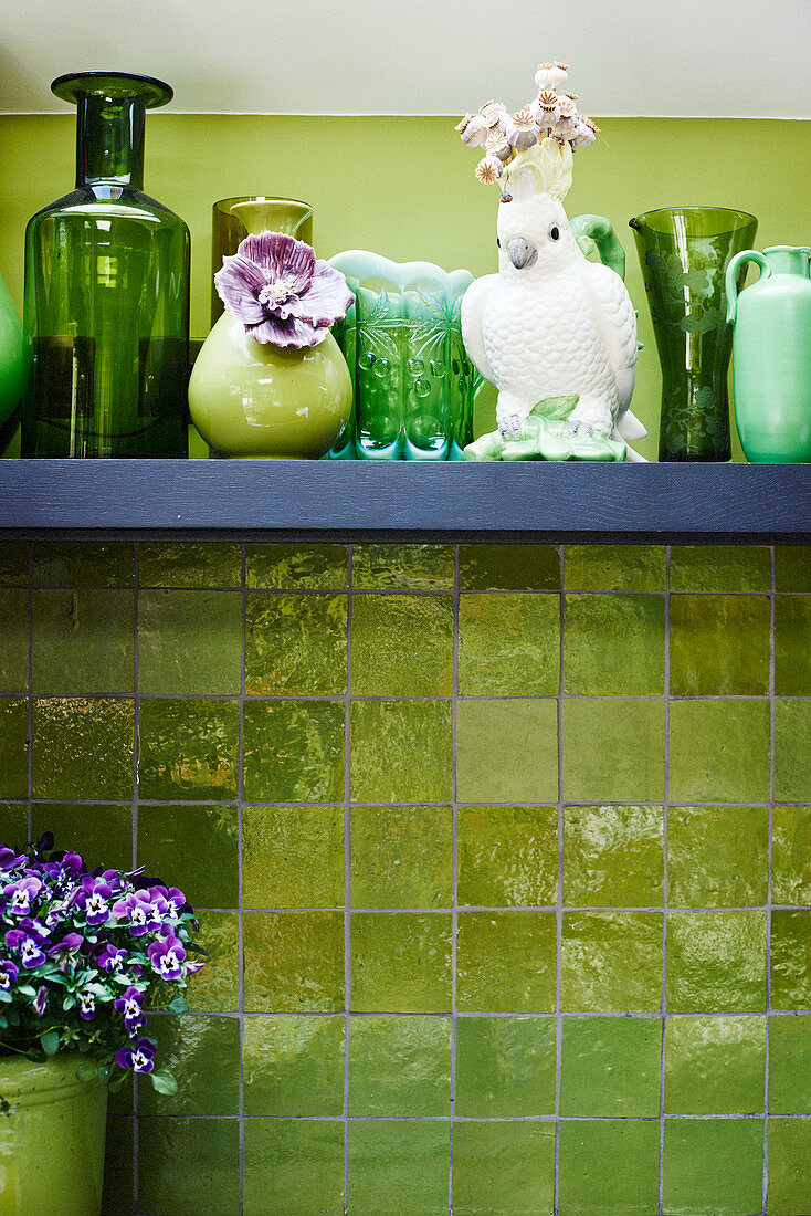 Bird ornament and green vases on shelf on green wall