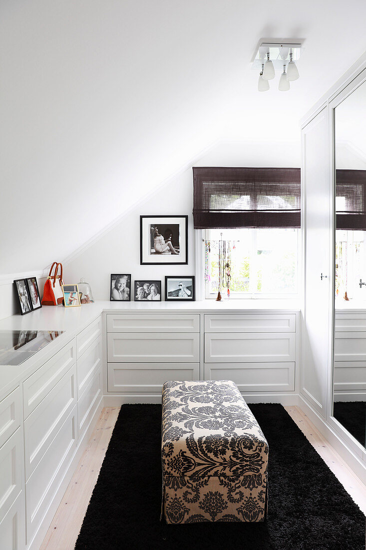 White fitted drawers and ottoman in dressing room