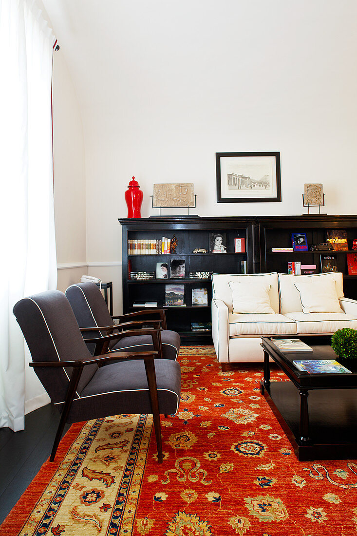 Black armchairs, pale sofa and black sideboard in elegant lounge