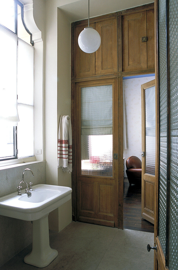 Old wooden door with frosted glass panels and cupboards above in bathroom