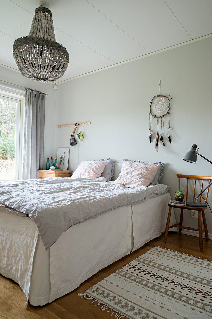 Beaded chandelier above bed with linen valance in bright bedroom