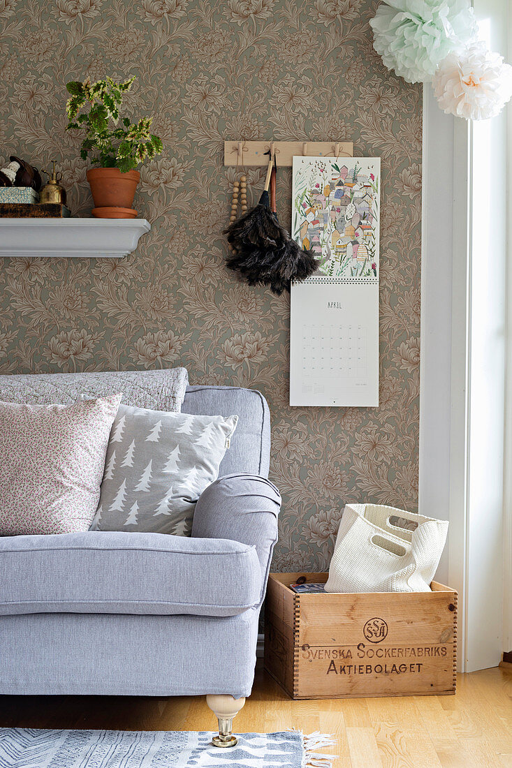 Vintage-style floral wallpaper behind grey sofa