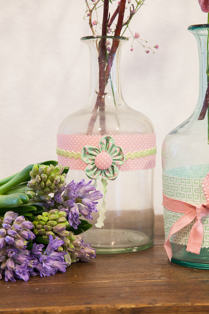 Hyacinths next to bottles decorated with fabric trim and fabric flowers