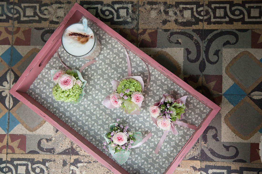 Kleine Blumensträußchen auf einem Tablett auf altem Fliesenboden