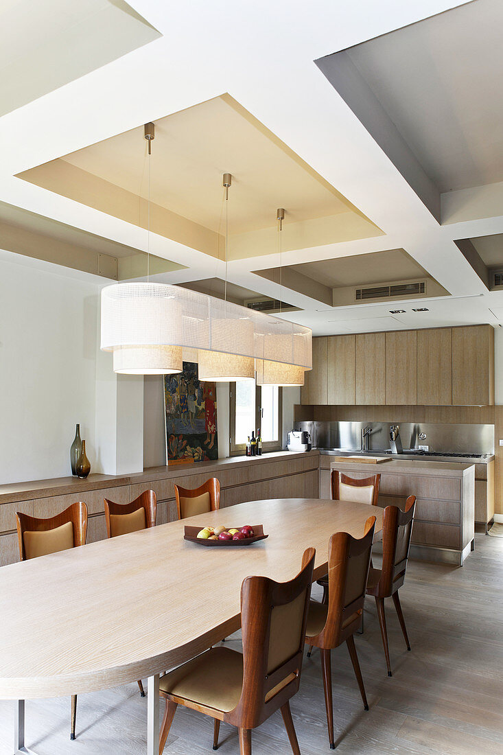 Curved chairs at dining table below modern coffered ceiling