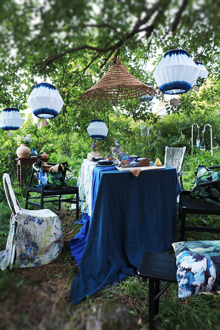 Set table below white and blue lanterns in garden