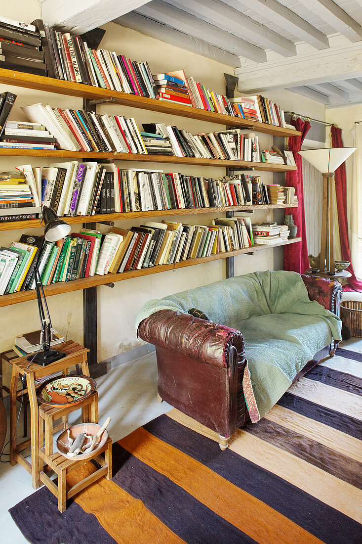 Wohnzimmer im Vintage-Stil mit altem Sofa unter den Bücherregalen