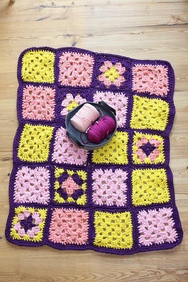 Crocheted blanket in purple, pink and yellow made from jersey yarn