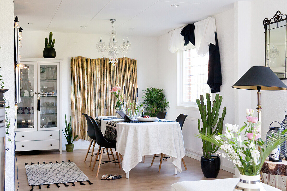 Table, black shell chairs, bamboo screen and glass-fronted cabinet in dining room