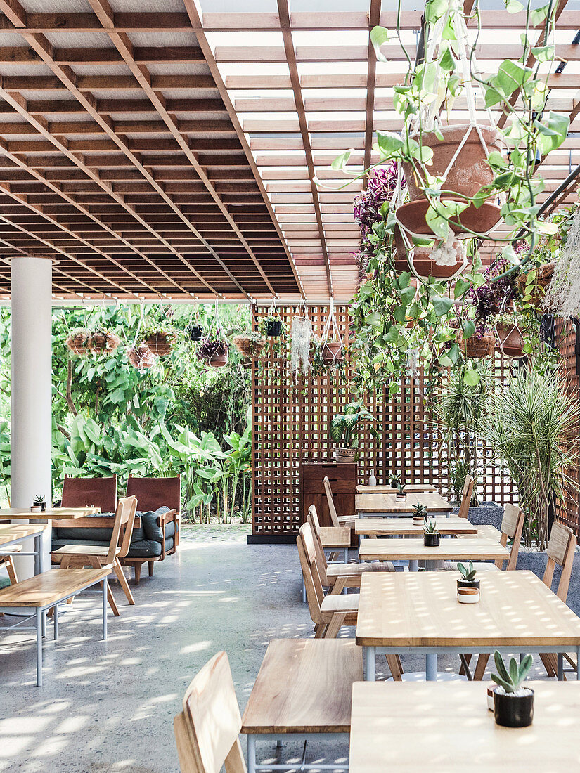 Large terrace with tables, chairs and benches, surrounded by wooden grids for privacy