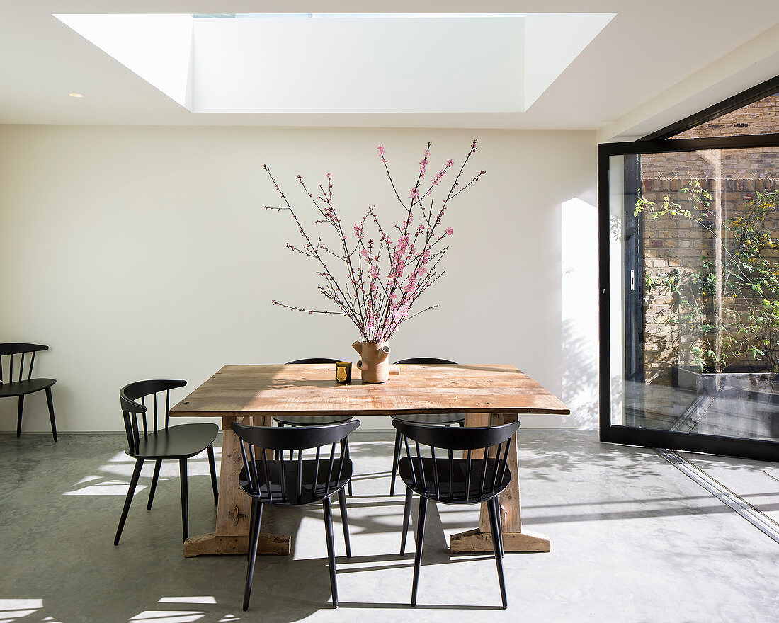 Black chairs around wooden table below skylight in dining room
