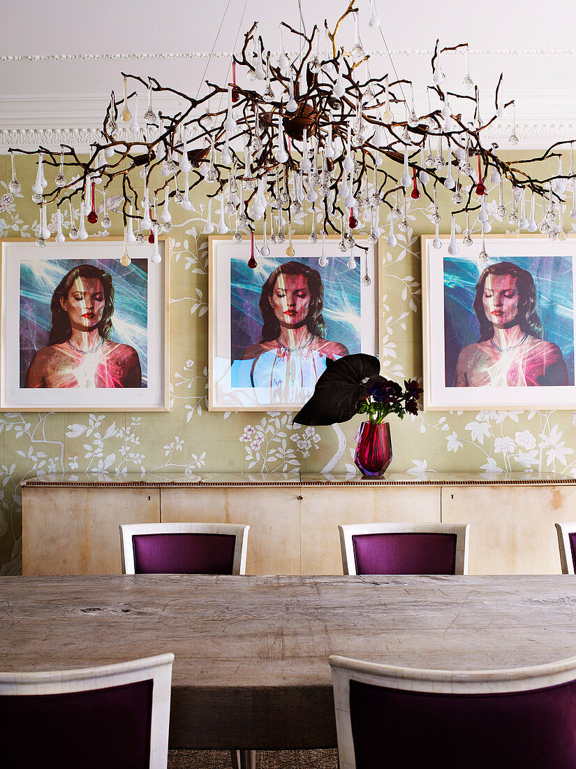 Designerleuchte über langem Esstisch mit bordeaux-roten Polsterstühlen, Triptychon Portrait an der Wand
