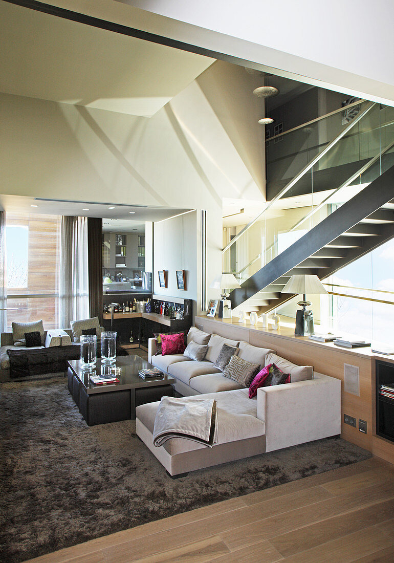 Modern living room with staircase behind glass wall