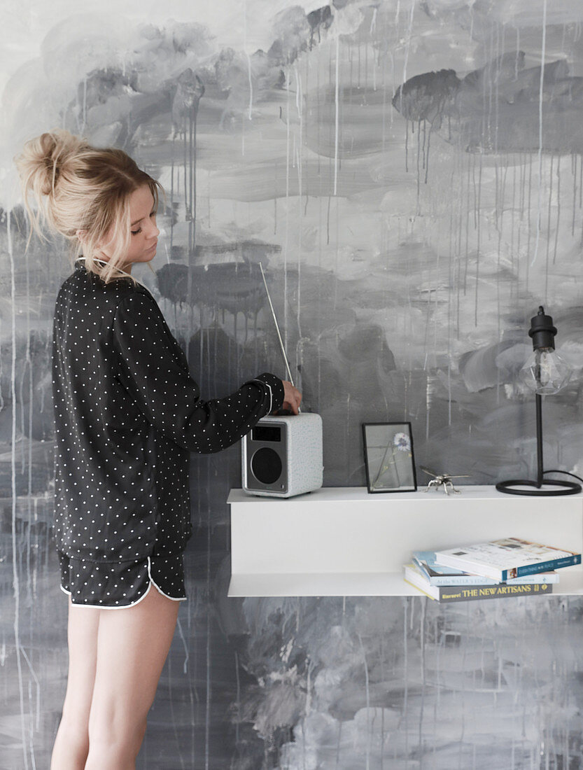 Junge Frau im gepunkteten Pyjama vor grau bemalter Wand