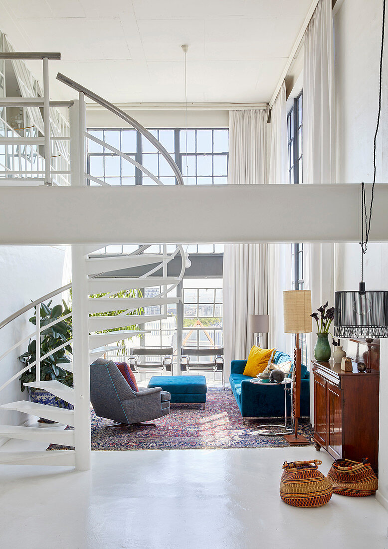 Blaue und graue Polstermöbel und Wendeltreppe in offenem Wohnraum mit doppelter Raumhöhe