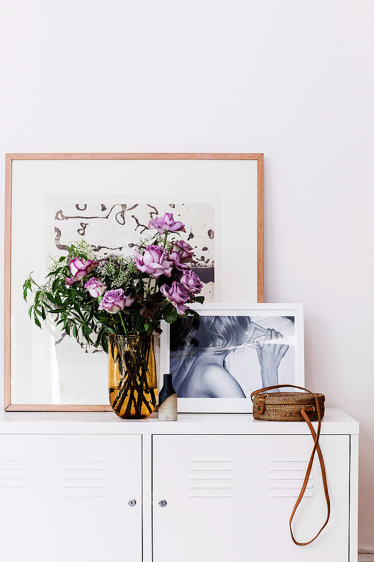 Bouquet of purple roses and pictures on the sideboard