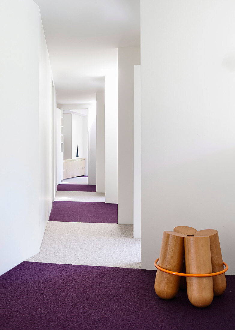 Wooden sculpture on purple carpet in white hallway
