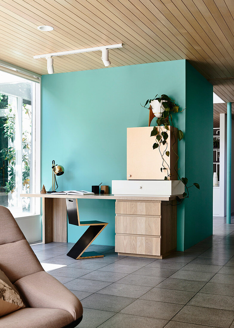 Zig-Zag-Stuhl und Schreibtisch an türkisfarbenem Raumteiler in offenem Wohnraum