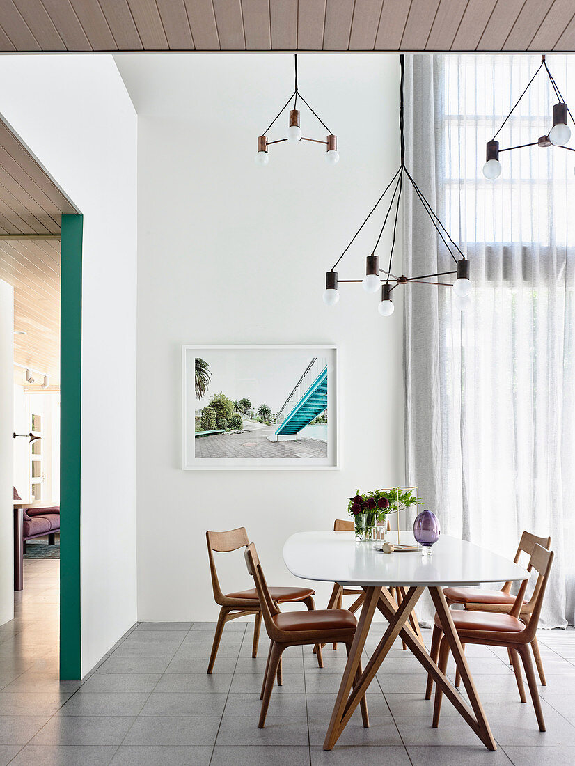 White dining table with chairs, designer lamp above
