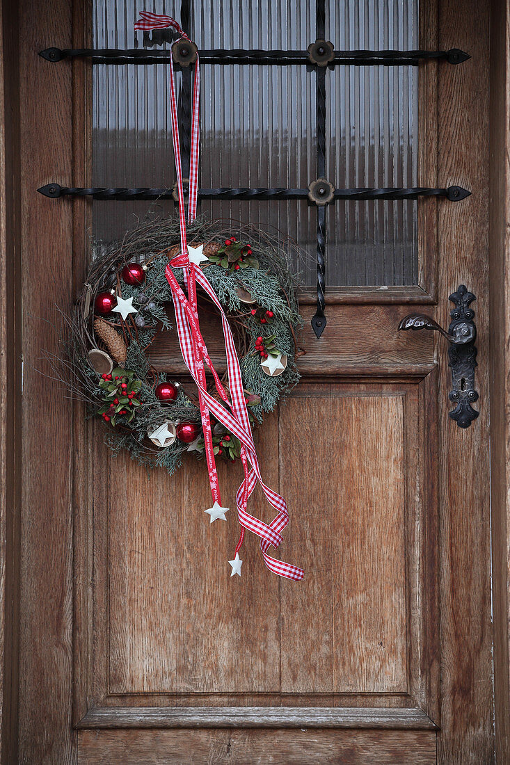 Christmas wreath with red and white ribbon on front door